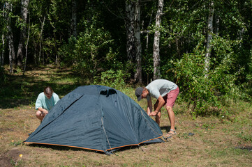 Caucasian man and woman pitching tent outdoors. 