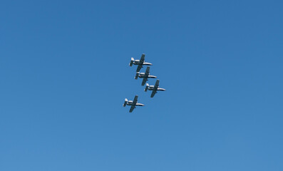 Four fighter jet in V shape in sky. Squadron. Air Force Day. Aircraft squadron on a mission. US air force. Military air force fighter jet airplane in full flight against blue sky. Air force jet