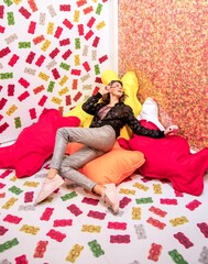 Beautiful cute woman laying on colourful pillows on the floor, while wall and floor is full of...