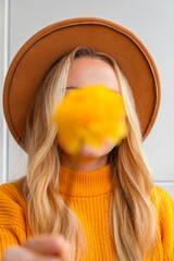 Woman faceless yellow sweater closing eyes with orange dahlia into camera Autumn Fall Bouquet for...