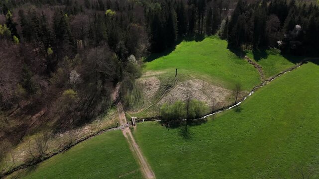 Luftaufnahme eines sonnigen Huegels in Oberbayern, Deutschland mit offener Wiese und der Mariensaeule. Ideal fuer Naturfreunde, Wanderungen und ruhige Ausfluege.