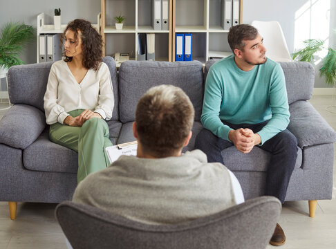 Wife and husband quarrel during conflict in psychotherapy session with psychologist, tackling divorce issues, fostering family consultation in a space dedicated to resolving challenges and tension.