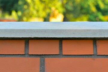 View of the brick base. Brick wall with white finished top with polished white capstone. Brick base. Brick background with polished headstone. Building and construction concept.