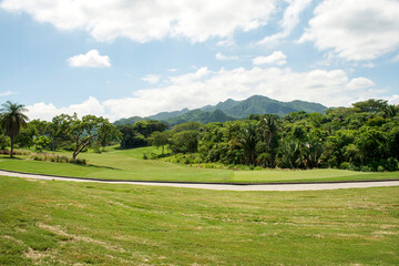 Tropical golf course fairway with lush mountains and blue sky