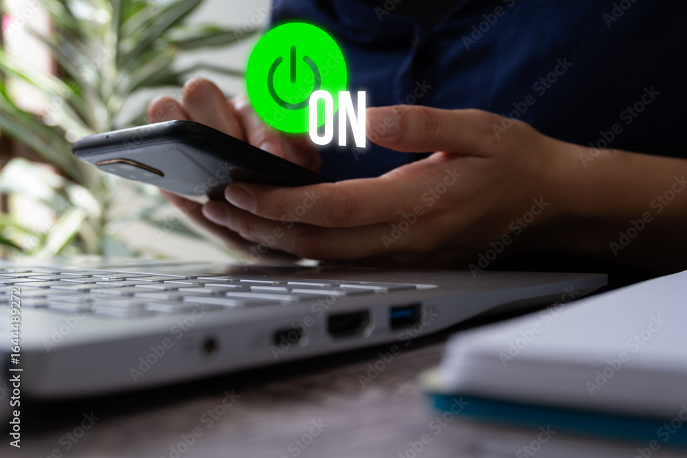 Poster businesswoman in front of a computer holding a smartphone with a floating icon of a power sign with 