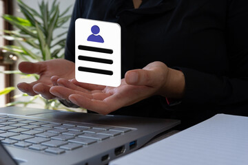 Businesswoman in front of a laptop holding a 3D icon of a resume with both hands