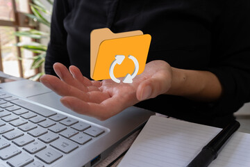 Businesswoman in front of a laptop holding a 3D folder icon and round refresh arrows