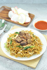 Indonesian style stir fry noodles with beef, egg,  green mustard, and crackers.