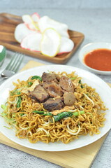Indonesian style stir fry noodles with beef, egg,  green mustard, and crackers.