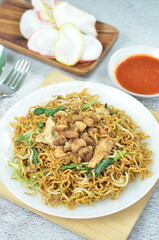 Indonesian style stir fry noodles with chicken, egg,  green mustard, and crackers.
