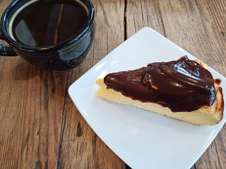 Pastel de Queso cubierto con chocolate y una taza de café, fotografía gastronómica con teléfono móvil. Toma Horizontal.