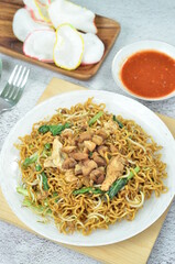 Indonesian style stir fry noodles with chicken, egg,  green mustard, and crackers.