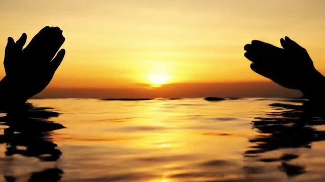 Silhouette of hands in water during chhath puja at sunset