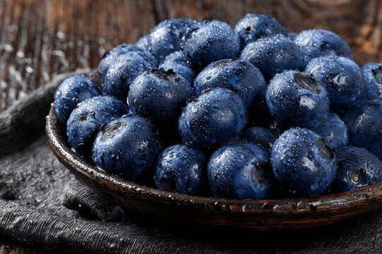National Blueberry Month is commemorated with a scene of fresh blueberries in a rustic bowl on a wooden table, surrounded by scattered berries, showcasing vibrant colors and natural textures - Powered by Adobe
