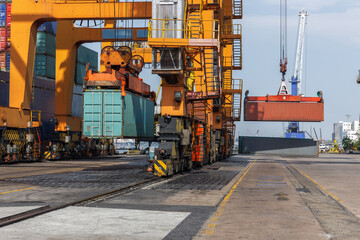 A busy shipping port scene with large gantry cranes lifting cargo containers from trains and...
