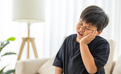 Young child experiencing toothache, tooth decay, childhood dental pain. The child facial...