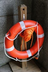 A bright orange life preserver, secured by ropes, hangs ready for use.