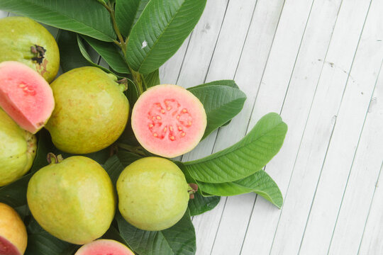 Flat lay of red guava fruit Psidium Guajava decorated with guava leaves. Slices of ripe and fresh red guava