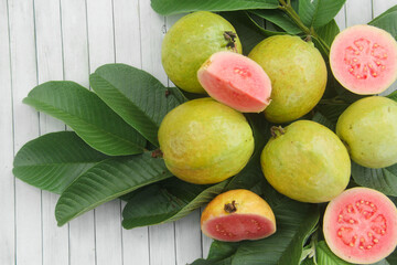 Flat lay of red guava fruit Psidium Guajava decorated with guava leaves. Slices of ripe and fresh...