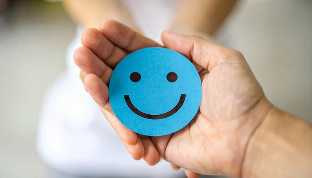 Hand holding blue paper cut happy smile face. Positive thinking, mental health assessment. World mental health day concept. Wellness and mental health. Detailed high quality image.