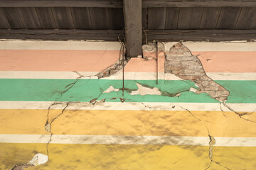 Colorful painted wall with pastel stripes cracked and peeling, revealing bricks underneath. Aesthetic grunge texture ideal for backgrounds, urban decay, or vintage art themes.