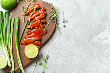 Board with canned fish in tomato sauce, lime, scallions and microgreens on grey table