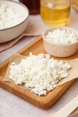 Wooden board with tasty cottage cheese on light background