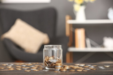 Jar with coins on table against blurred background. Savings concept