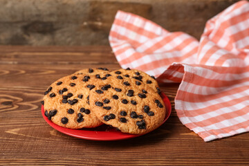 Plate of tasty cookies with chocolate chips on wooden background