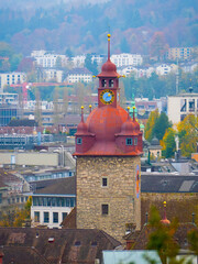 Clock tower of Luzern City Hall in Switzerland with red dome, Roman numeral clock face, stone...