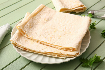 Plate with fresh lavash on green wooden background