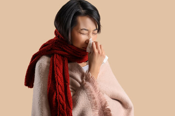 Ill Asian woman with tissue on beige background