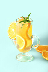 Glass of infused water with orange slices on blue background