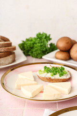 Plate with triangles of tasty processed cheese and toast on pink tile background, closeup