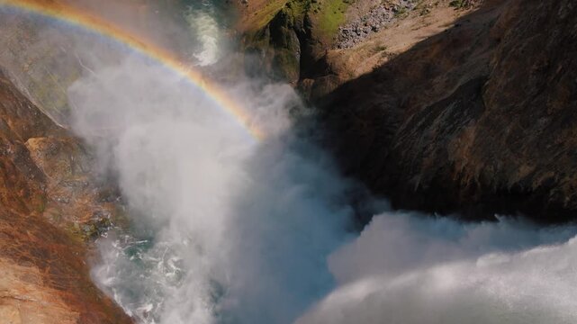 Brink of Lower Yellowstone Falls showing river and canyon with rainbow.