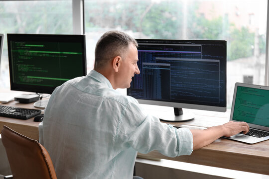 Mature male programmer working in light office