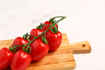 Wooden board with fresh cherry tomatoes on white background