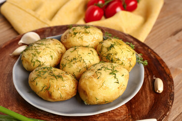 Plate of boiled baby potatoes with dill on wooden background