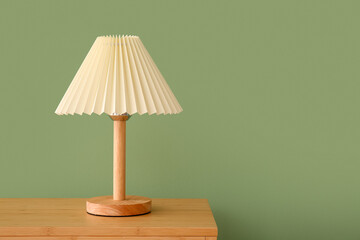 Lamp on wooden table near green wall