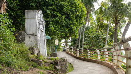 Curved pedestrian walkway at Taman Muaro Lasak, Padang, Indonesia, lined with tropical trees and coastal vegetation, offering scenic seaside views and peaceful walking experience.