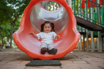 happy toddler baby girl sliding and playing at playground