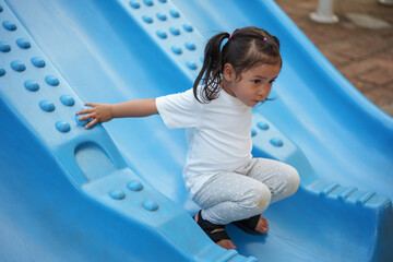happy toddler baby girl sliding and playing at playground