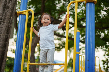 happy toddler girl playing and climbing on outdoor playground at park