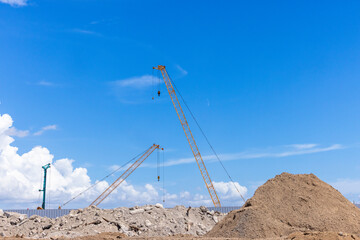 Construction site with construction crawler cranes and multi storey unfinished buildings, Many high rise cranes and industrial construction equipment, Contruction site bl;ue sky background.