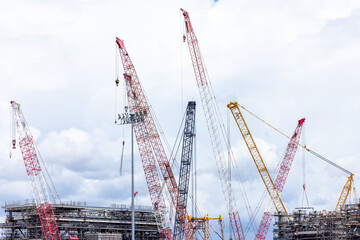 Construction site with construction crawler cranes and multi storey unfinished buildings, Many high rise cranes and industrial construction equipment, Contruction site bl;ue sky background.