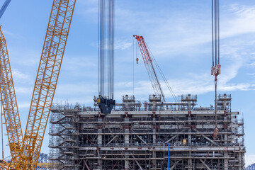 Construction site with construction crawler cranes and multi storey unfinished buildings, Many high rise cranes and industrial construction equipment, Contruction site bl;ue sky background.