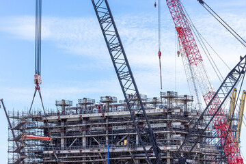 Construction site with construction crawler cranes and multi storey unfinished buildings, Many high rise cranes and industrial construction equipment, Contruction site bl;ue sky background.