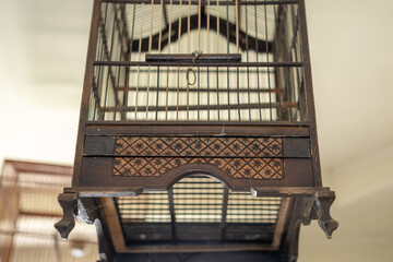 Close-up of a traditional wooden bird cage with intricate carved patterns, showcasing vintage...