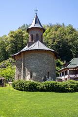 historic prislop monastery in romania, featuring the stone church with a steeple and a lush green...