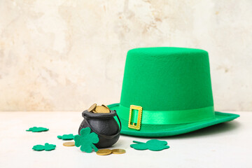 Pot with golden coins, leprechaun hat and clovers on light grunge background. St. Patrick's Day...